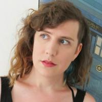 verily bitchie, a white woman with curly medium-length light brown hair wearing a tank top